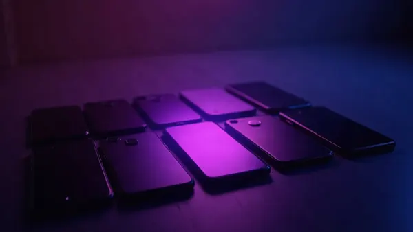 Mehrere aufgereihte Smartphones, ein violetter Scheinwerfer auf dem mittleren (Illustration zum Artikel)